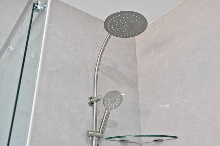 White tiled Sydney shower with a rain head, hand shower and frameless glass screen