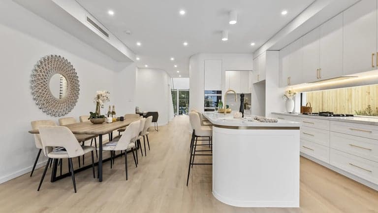 White Sydney kitchen with a curved island opening to a dining table