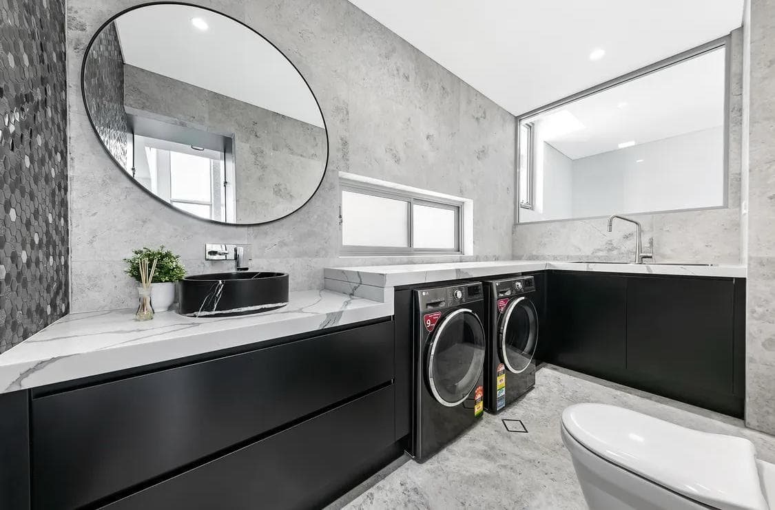 Sydney laundry renovation with black cabinets, a stone bench and paired machines