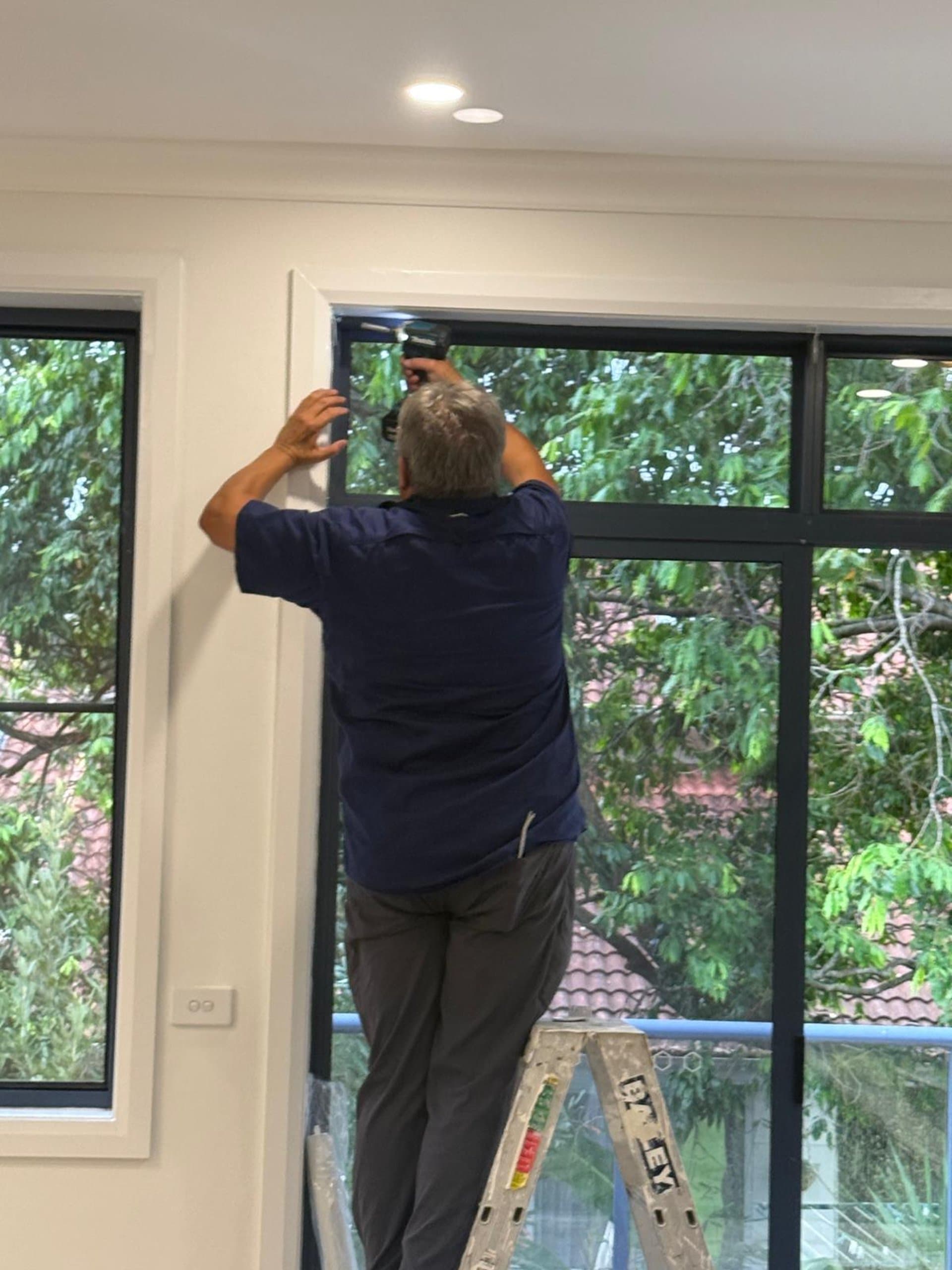 Custom window furnishing installation on a black-framed Sydney window
